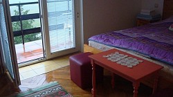 Ugaona garnitura u pastelnim tonovima za opuštanje uz TV u apartmanu Zlatiborski visovi  Detalj kuhinje: čist radni prostor, električni bokal i set šoljica za kafu i čaj  Spavaća soba u potkrovlju sa drvenim elementima koji pružaju toplinu i planinski šarm  Trpezarijski kutak sa prirodnom svetlošću za doručak uz pogled na zlatiborske bregove