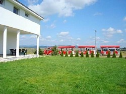 Pokrivena terasa sa drvenom ljuljaskom i garniturom za odmor u hladovini  Prostrana livada ispred kuce pogodna za fudbal badminton i sportske aktivnosti  Zlatiborski visovi dvoriste sa puno cveca i zelenila u mirnom delu Zlatibora  Letnjikovac sa velikim stolom za rucavanje na otvorenom tokom letnjih dana